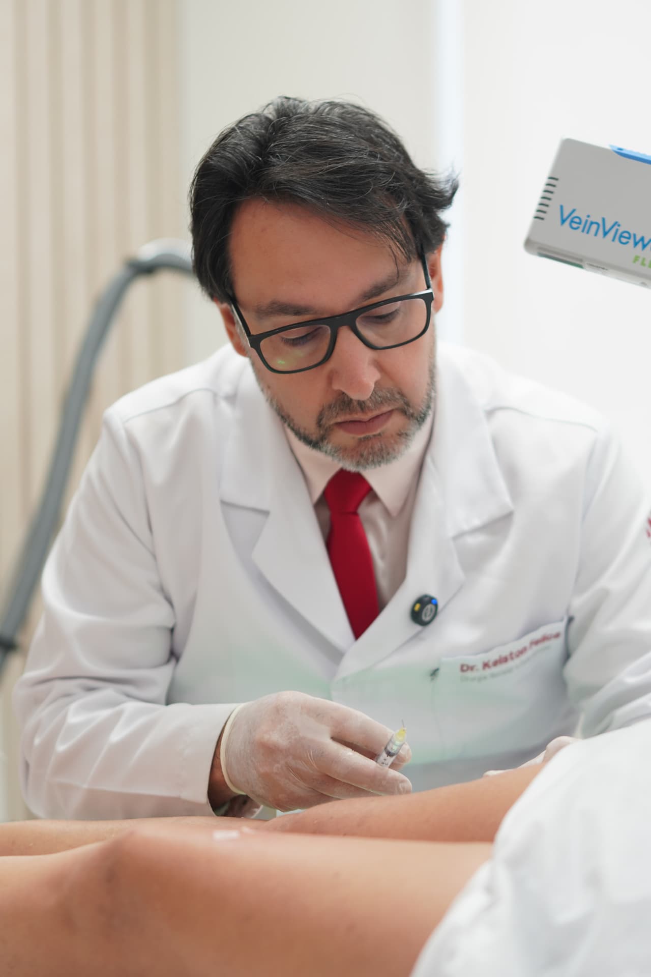 Dr. Kelston Felice em atendimento clínico avaliando a perna de um paciente